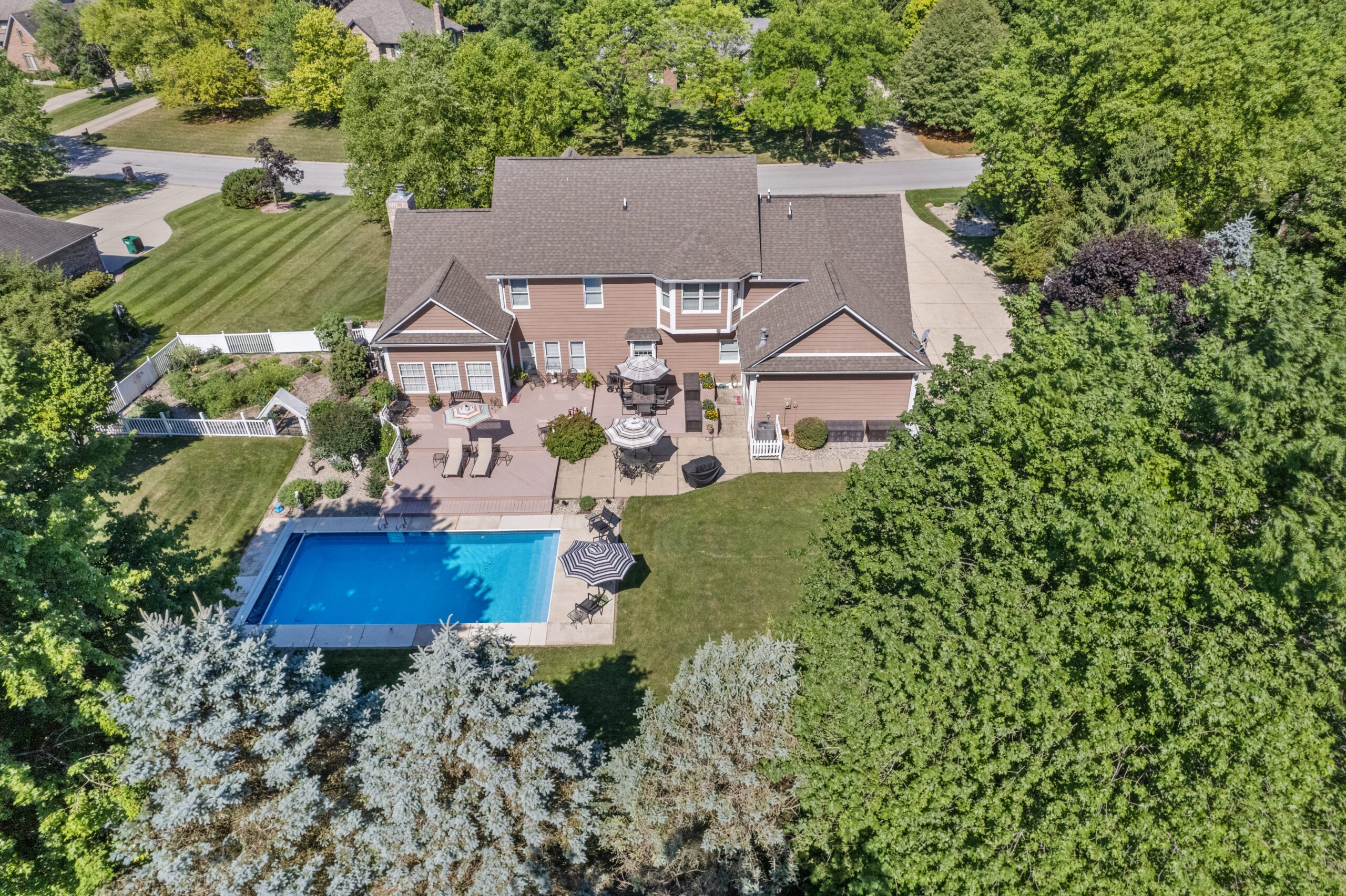 Aerial view of the back of a 2-storyt home with a swimming pool.