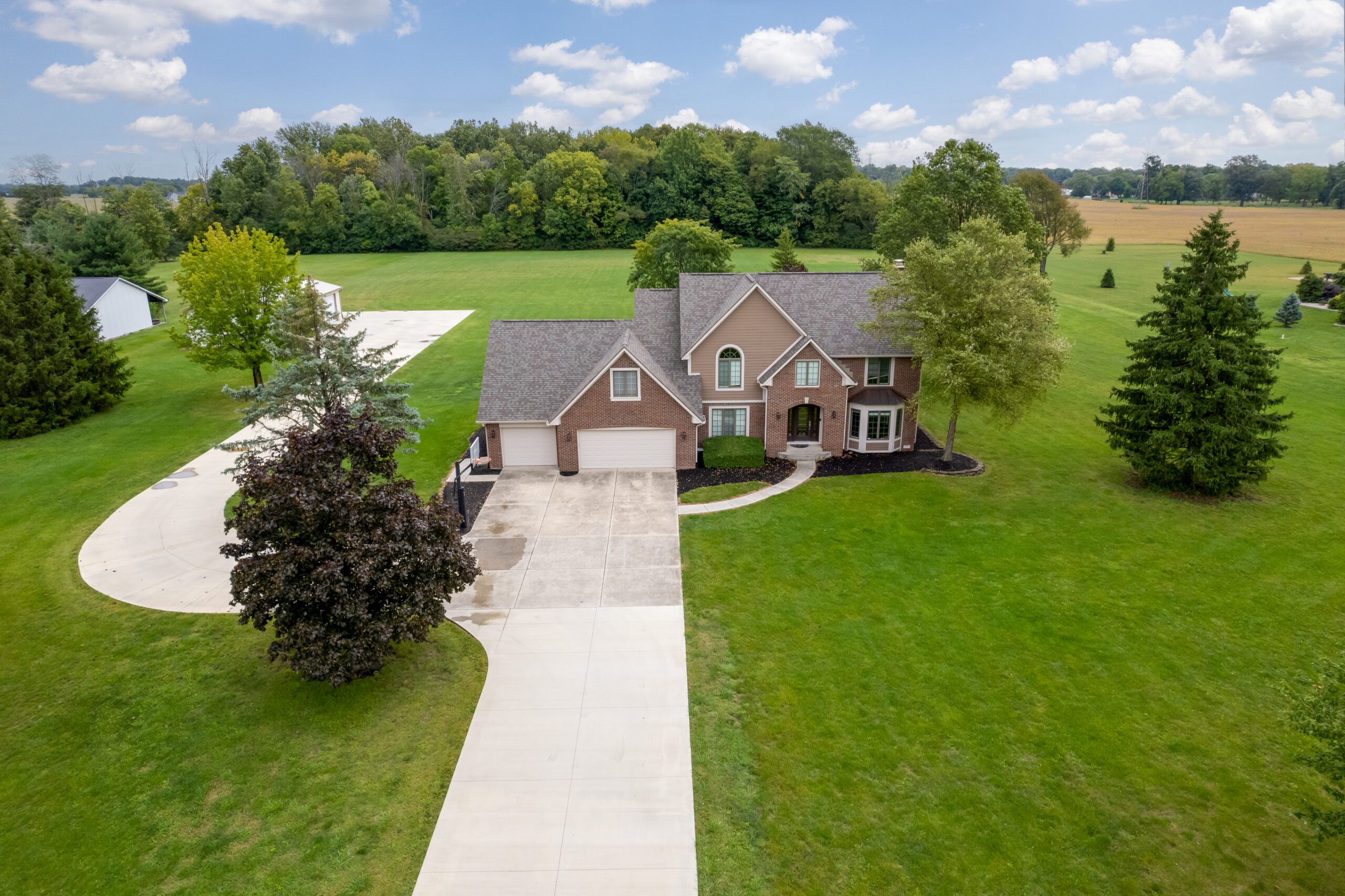 Aerial view of a home in the country on a large lot.